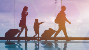 perhe kävelee matkalaukkujen kanssa, lapsi osoittaa sormella eteenpäin